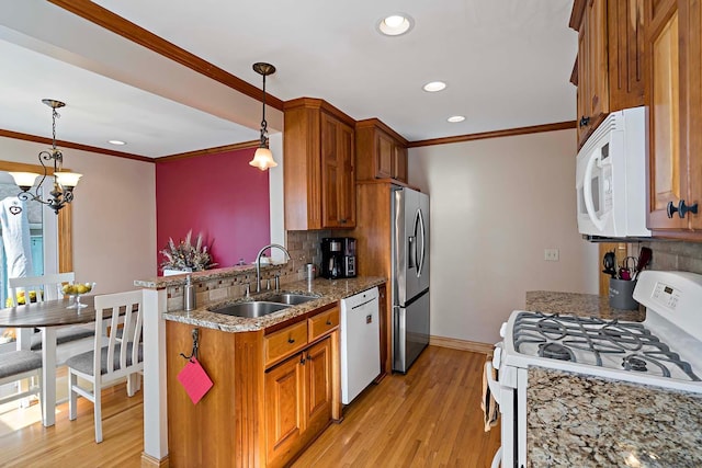 kitchen with sink, light hardwood / wood-style floors, hanging light fixtures, and white appliances