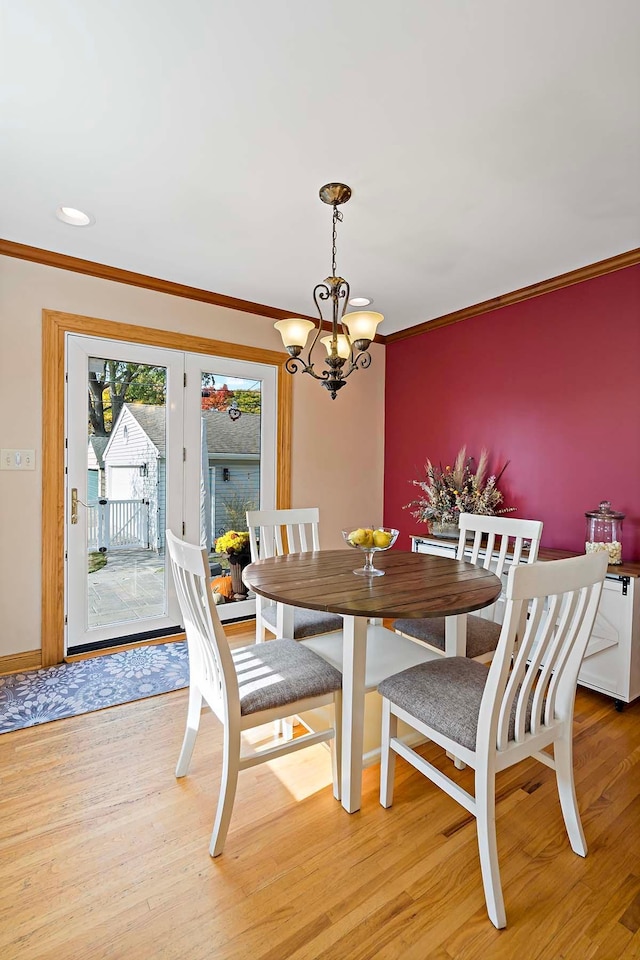 dining space featuring ornamental molding, a chandelier, and light wood-type flooring