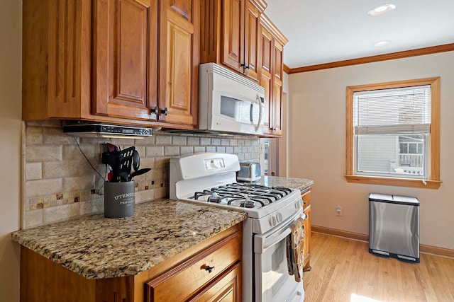 kitchen with white appliances, light hardwood / wood-style floors, crown molding, and light stone countertops