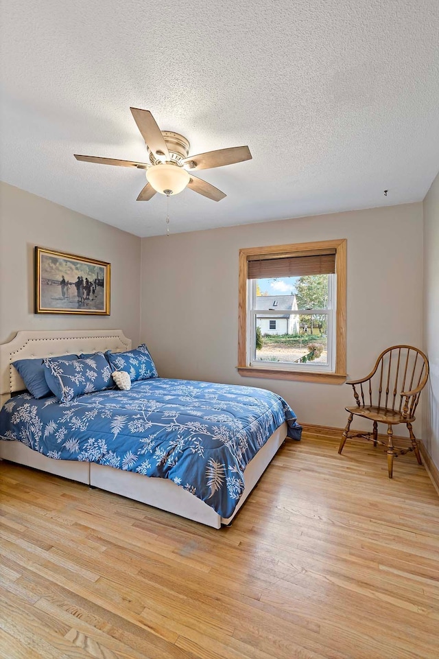 bedroom featuring light hardwood / wood-style flooring, a textured ceiling, and ceiling fan