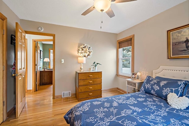 bedroom with a textured ceiling, light hardwood / wood-style floors, and ceiling fan