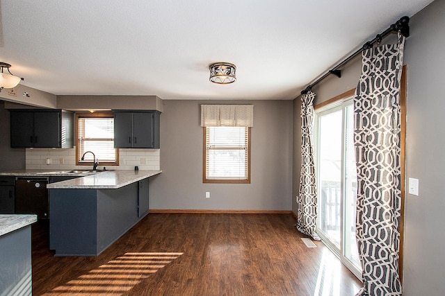 kitchen with backsplash, sink, dark hardwood / wood-style floors, light stone counters, and kitchen peninsula