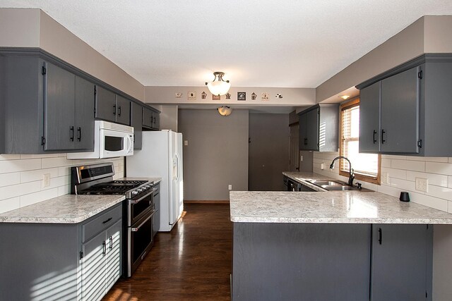 kitchen with gray cabinetry, sink, dark wood-type flooring, kitchen peninsula, and white appliances