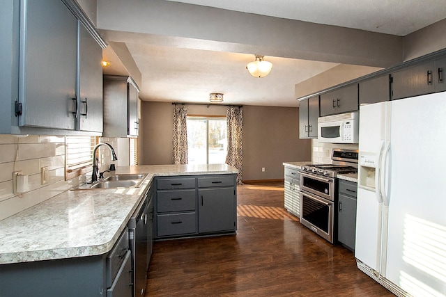 kitchen featuring kitchen peninsula, appliances with stainless steel finishes, backsplash, dark wood-type flooring, and sink