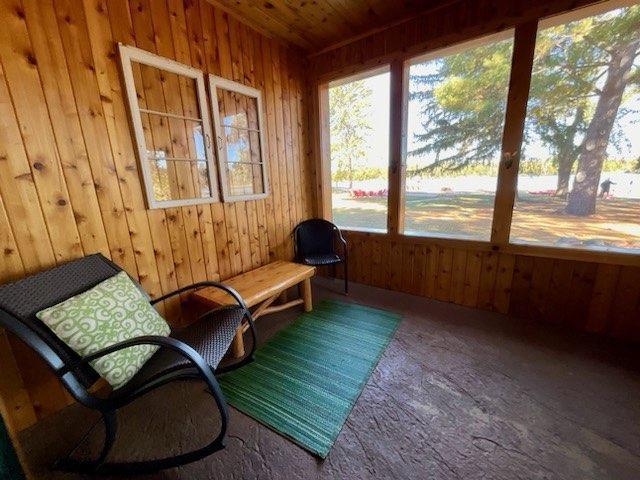 sunroom / solarium with carpet, wooden ceiling, and wooden walls