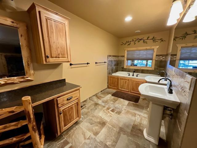 full bathroom with a sink, a garden tub, and stone finish flooring