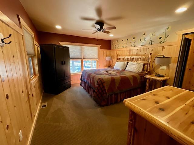 bedroom with wood walls, carpet flooring, visible vents, and recessed lighting