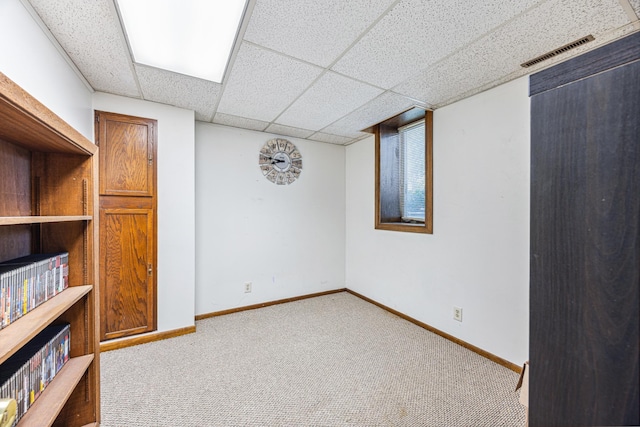 basement featuring light carpet and a paneled ceiling