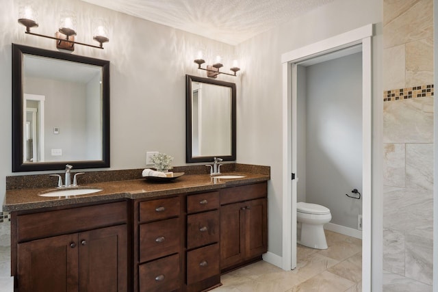 bathroom featuring vanity, a textured ceiling, and toilet