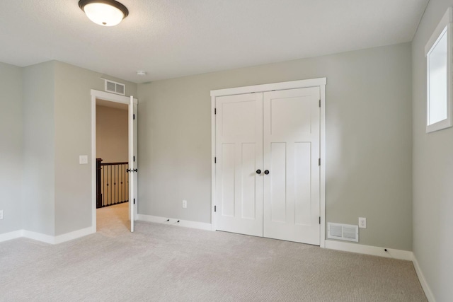 unfurnished bedroom featuring a closet, light carpet, and a textured ceiling