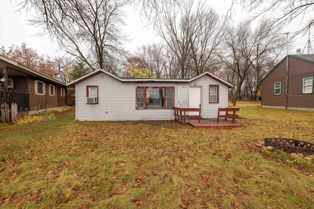 back of property featuring cooling unit, a lawn, and a fire pit