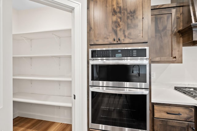 kitchen featuring gas stovetop, double oven, and light wood-type flooring