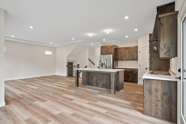 kitchen featuring a center island with sink, a breakfast bar, light hardwood / wood-style flooring, sink, and stainless steel appliances