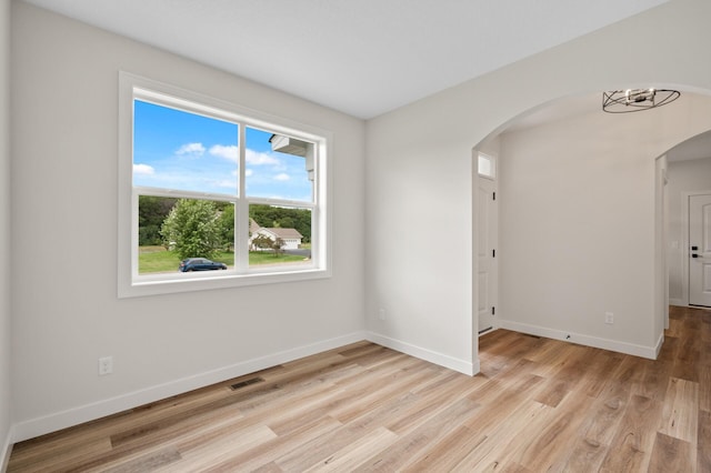 spare room with a chandelier and light hardwood / wood-style flooring