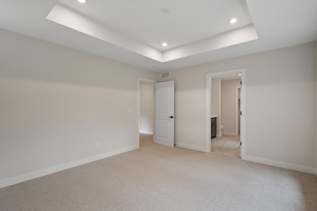 unfurnished bedroom with a tray ceiling and light colored carpet