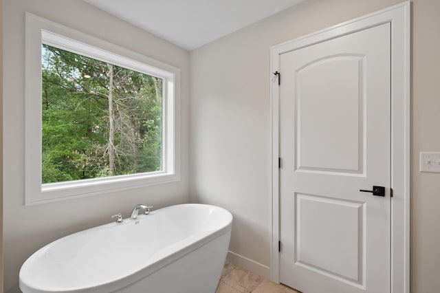 bathroom with a tub, a healthy amount of sunlight, and tile patterned floors