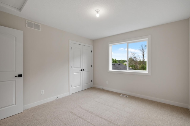 unfurnished bedroom featuring a closet and light colored carpet