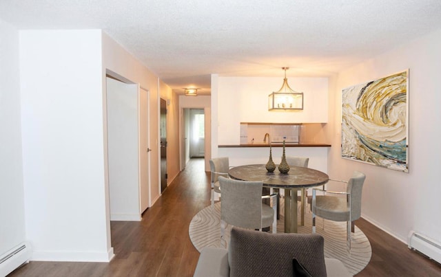 dining space featuring an inviting chandelier, a textured ceiling, baseboard heating, and dark wood-type flooring