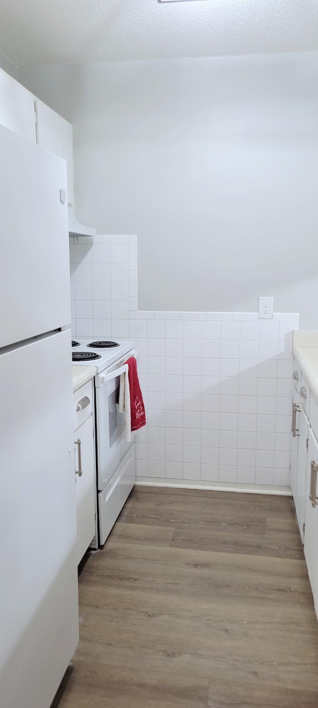 kitchen featuring light hardwood / wood-style flooring, white cabinets, and white appliances