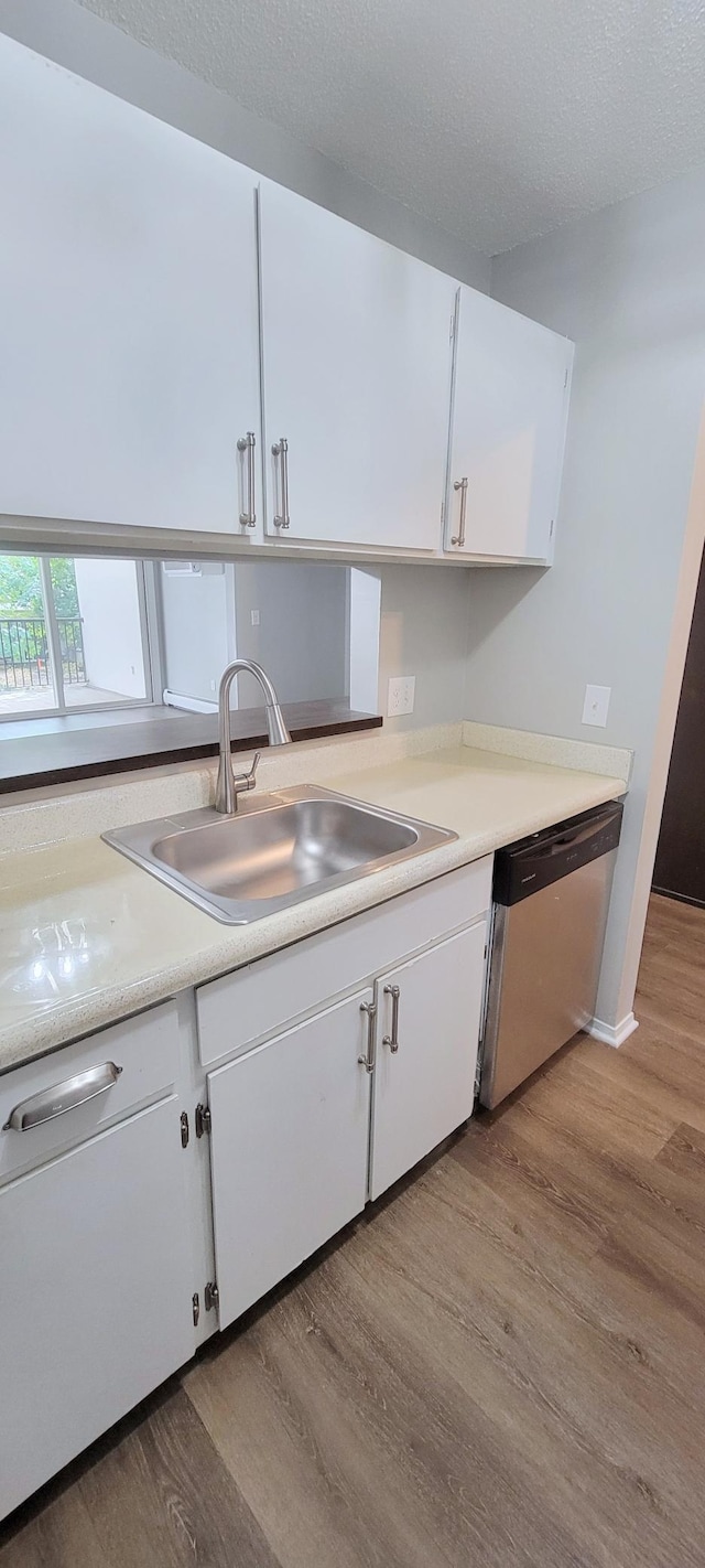 kitchen with white cabinetry, light hardwood / wood-style floors, sink, and stainless steel dishwasher