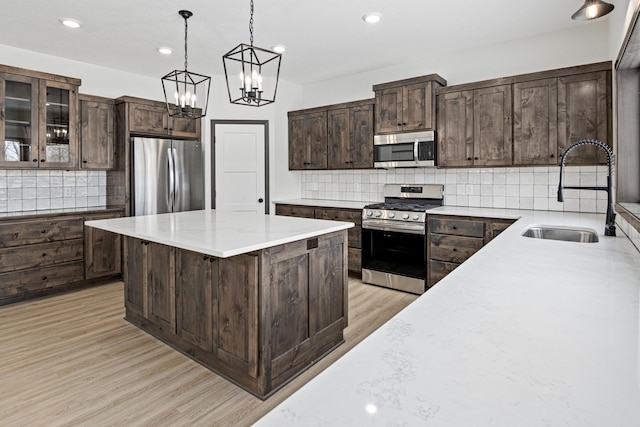 kitchen with tasteful backsplash, dark brown cabinets, light wood-type flooring, sink, and stainless steel appliances