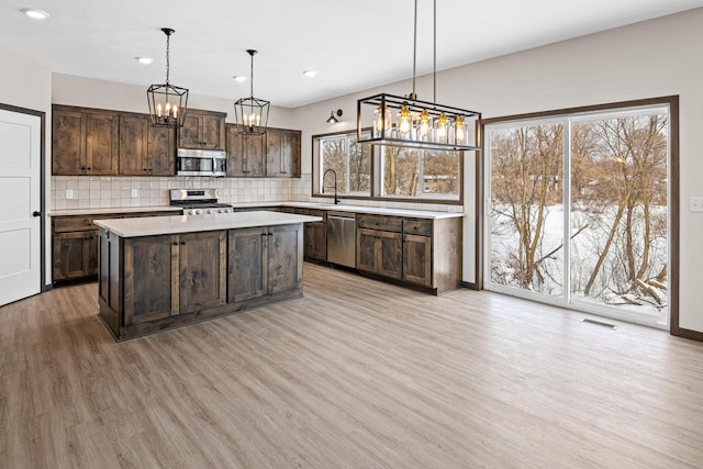 kitchen featuring pendant lighting, appliances with stainless steel finishes, dark brown cabinetry, and plenty of natural light