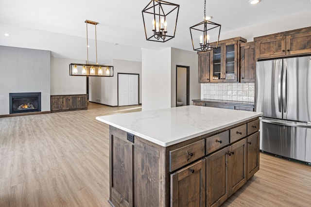 kitchen with a center island, decorative light fixtures, light wood-type flooring, and stainless steel fridge