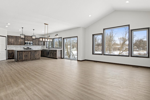 unfurnished living room featuring lofted ceiling, sink, and light hardwood / wood-style flooring