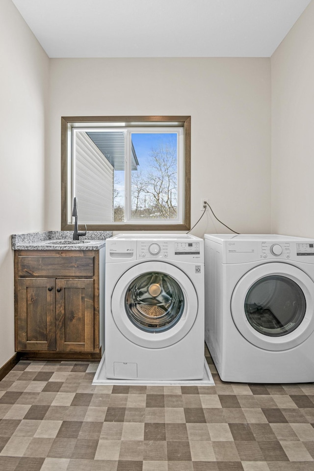 clothes washing area featuring sink, washing machine and dryer, and cabinets