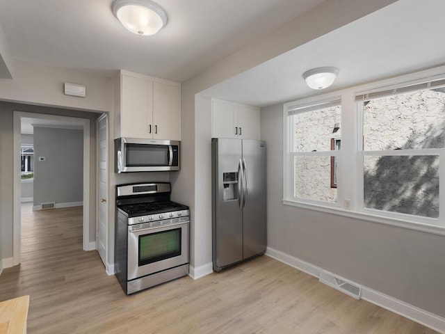 kitchen with white cabinets, stainless steel appliances, and light wood-type flooring