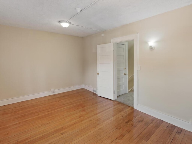 spare room featuring light hardwood / wood-style flooring and a textured ceiling