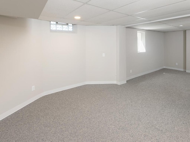 basement with a paneled ceiling, carpet floors, and plenty of natural light