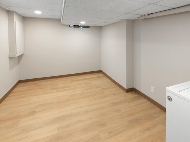 basement with light hardwood / wood-style floors, washer / clothes dryer, and a paneled ceiling