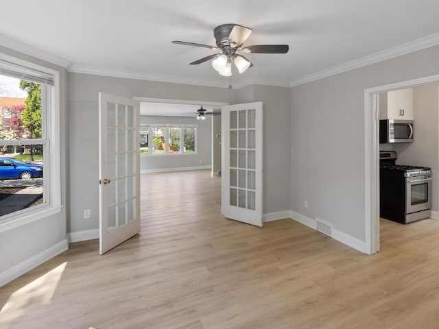 spare room featuring french doors, light wood-type flooring, and a healthy amount of sunlight