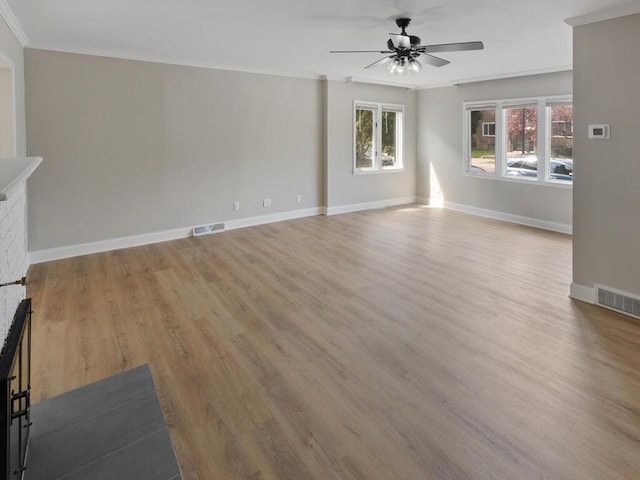 unfurnished living room with light hardwood / wood-style floors, crown molding, a fireplace, and ceiling fan