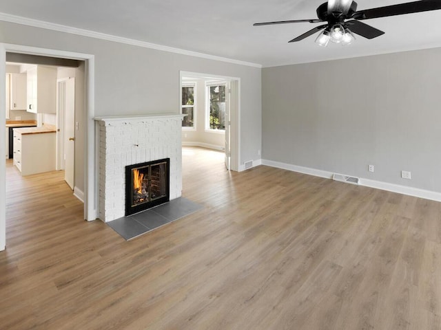 unfurnished living room with ornamental molding, hardwood / wood-style floors, a brick fireplace, and ceiling fan