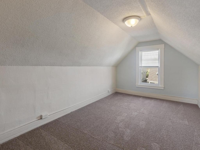 bonus room with carpet, vaulted ceiling, and a textured ceiling