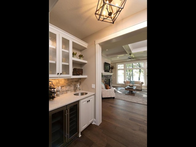 bar featuring sink, dark hardwood / wood-style flooring, white cabinetry, beamed ceiling, and pendant lighting