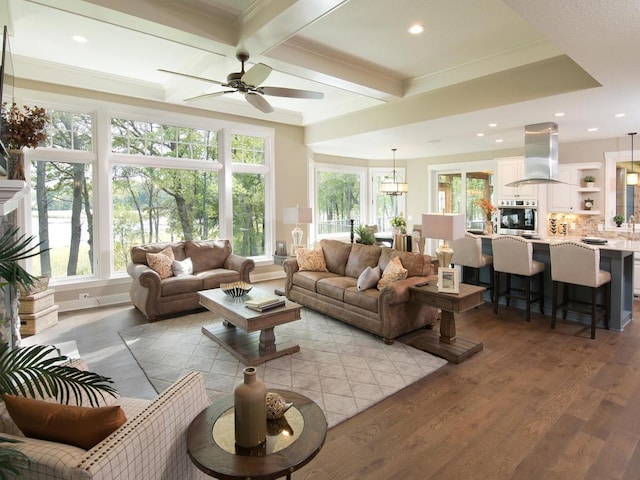 living room featuring crown molding, light hardwood / wood-style flooring, ceiling fan, and plenty of natural light