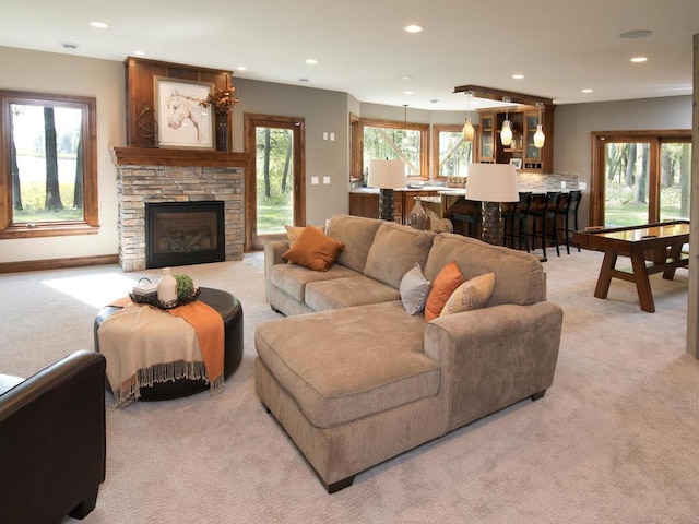 living room with light carpet, a healthy amount of sunlight, and a stone fireplace