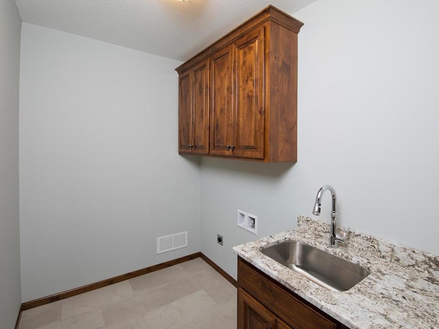 clothes washing area with hookup for a washing machine, sink, a textured ceiling, electric dryer hookup, and cabinets