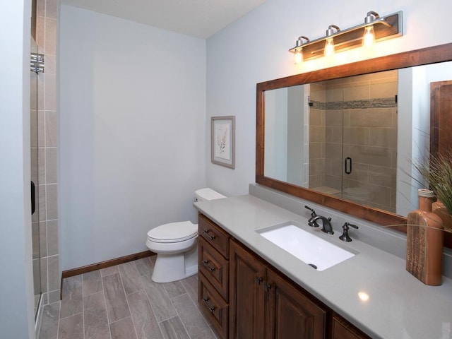 bathroom with vanity, a shower with shower door, and toilet