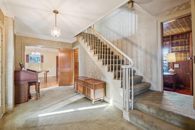 stairway featuring carpet, a notable chandelier, a healthy amount of sunlight, and crown molding