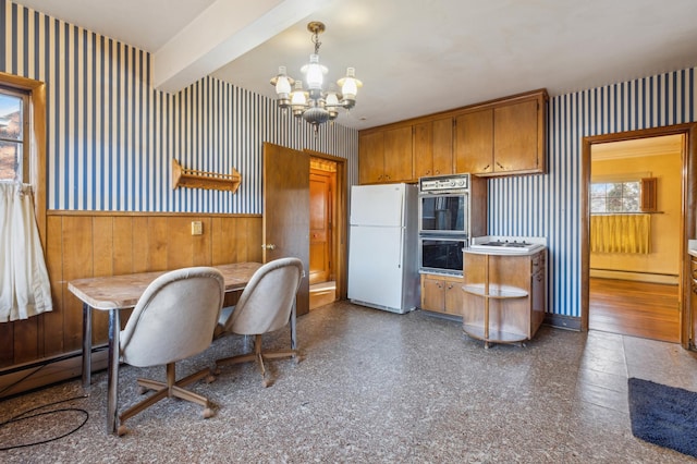 kitchen with pendant lighting, white refrigerator, black double oven, beamed ceiling, and a chandelier