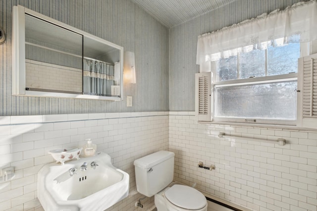 bathroom featuring sink, tile walls, and toilet