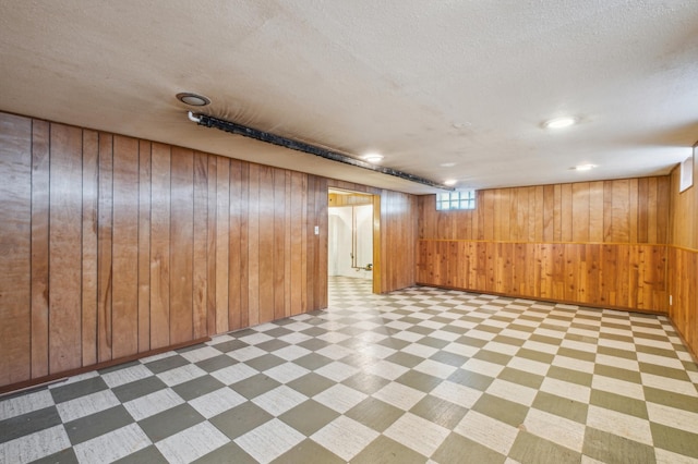 basement featuring a textured ceiling and wooden walls