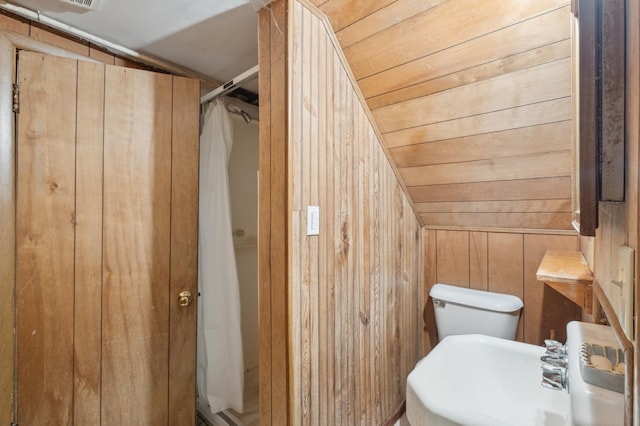 bathroom featuring wooden ceiling, wood walls, a shower, lofted ceiling, and toilet