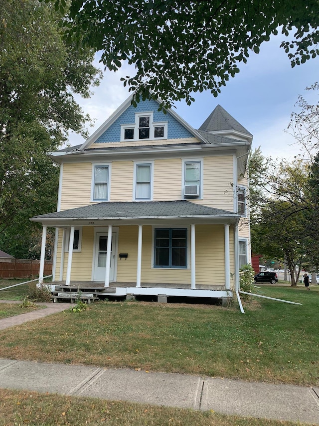 view of front of house featuring covered porch, a front yard, and cooling unit