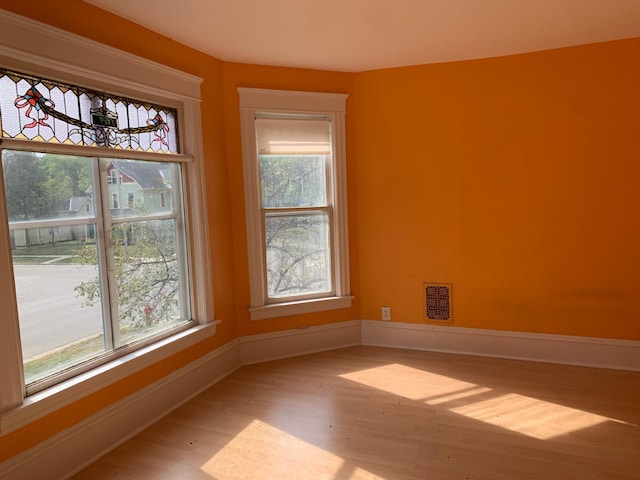 unfurnished room with hardwood / wood-style floors and a healthy amount of sunlight