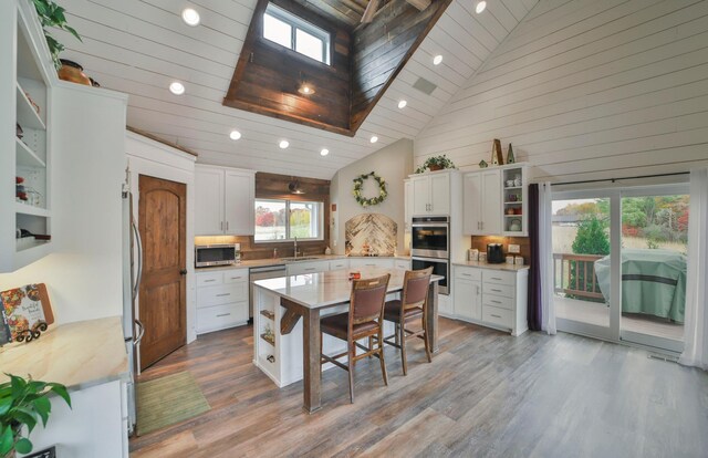 kitchen with white cabinetry, a kitchen breakfast bar, a kitchen island, stainless steel appliances, and light hardwood / wood-style floors